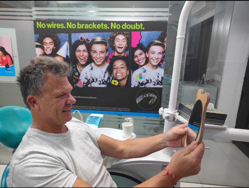 Patient checking his new smile in a hand mirror on the dental chair