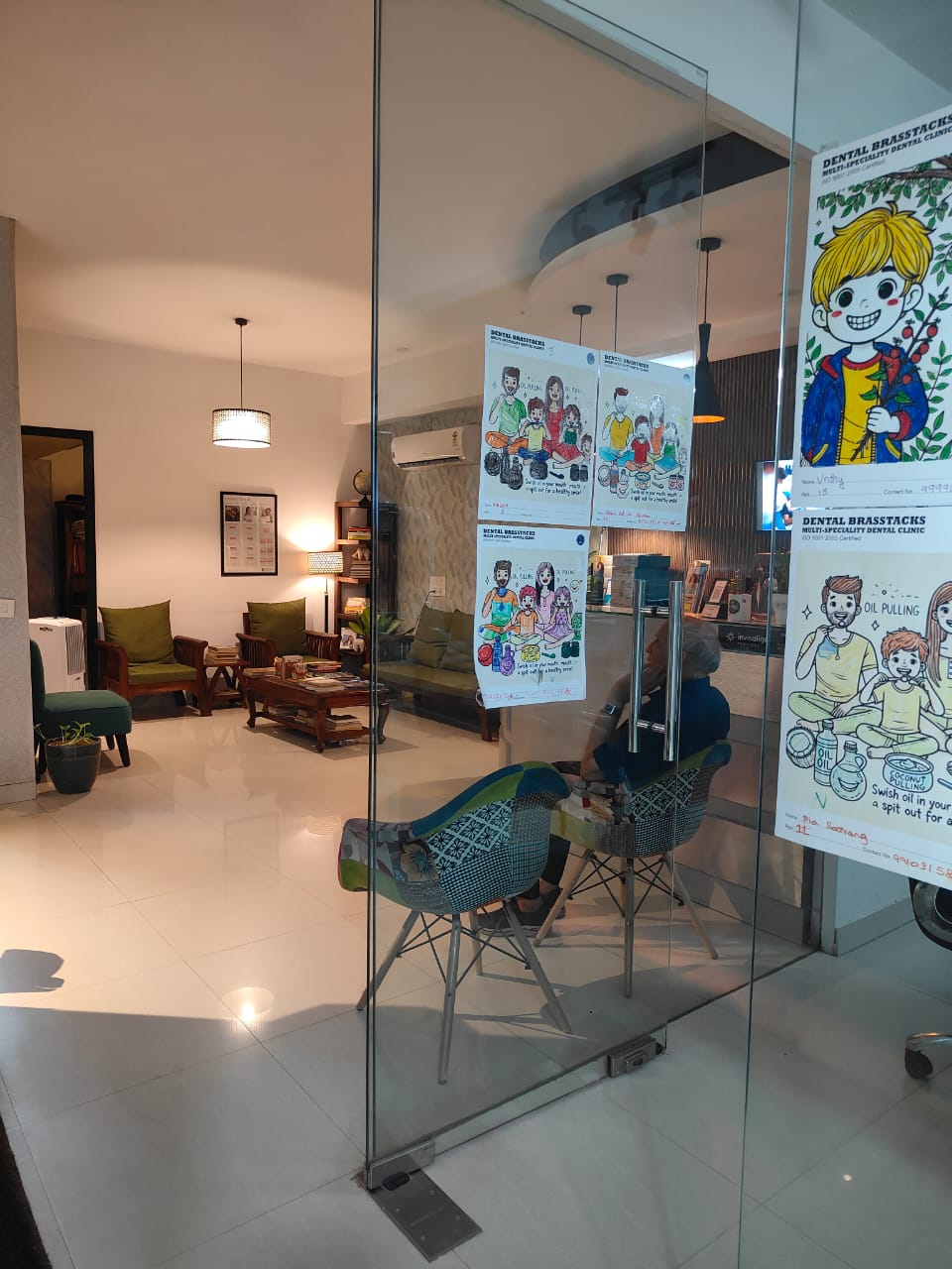 Patient lounge at Dental Brasstacks with sofas, cushions and children's artwork on the glass partition