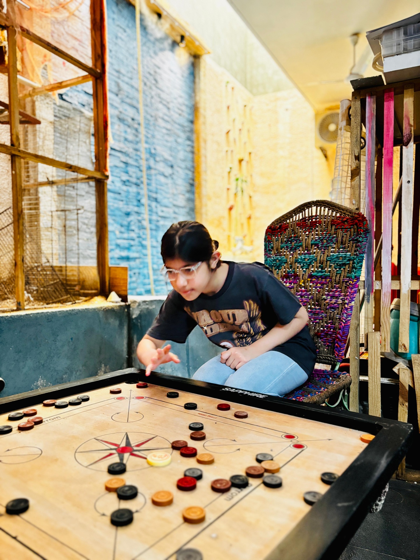 A child playing carrom beside the indoor waterfall at Dental Brasstacks Gurgaon