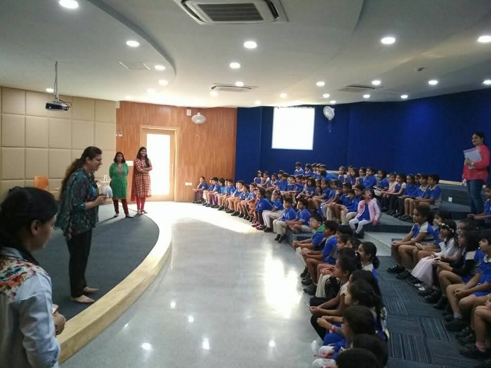 Dr. Nisha Bali addressing a full school auditorium of children during a dental health talk in Gurgaon