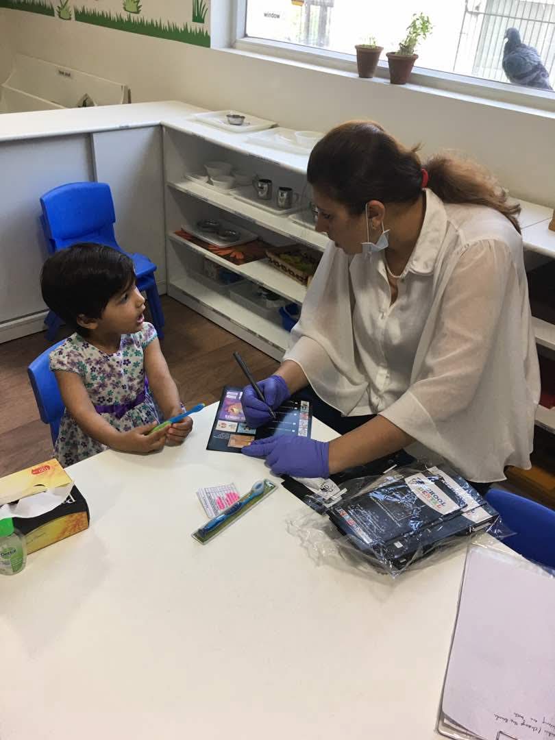Dr. Nisha Bali teaching a young child correct brushing technique at a preschool